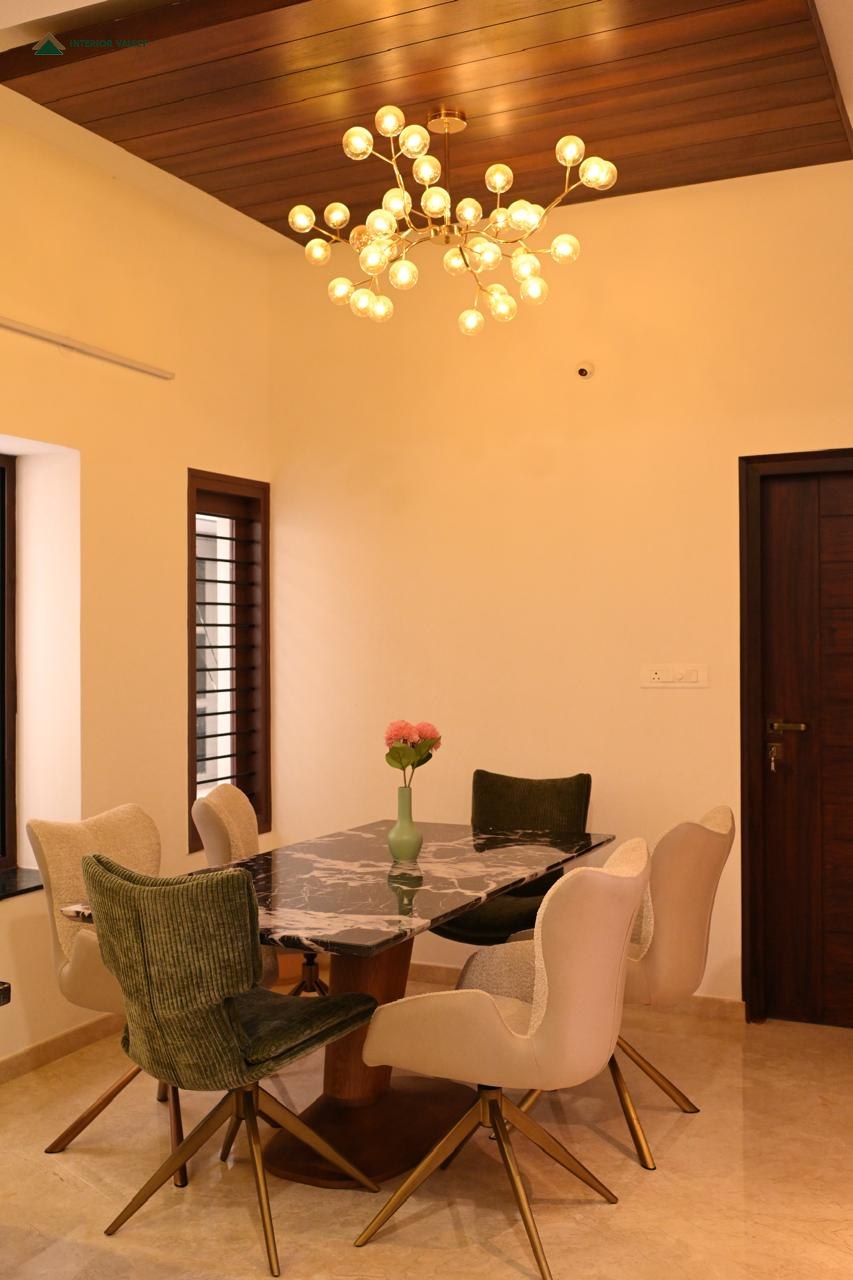 Dining area beneath a sculptural chandelier and a wood-lined ceiling