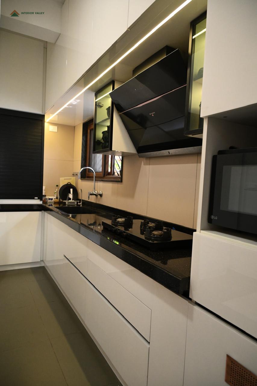 Galley kitchen with glossy white cabinetry and a dark counter
