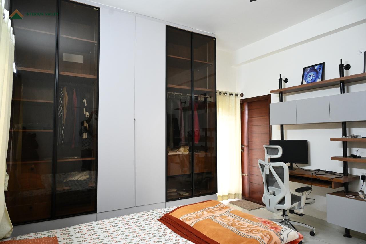 Bedroom wardrobe with black glass doors beside a built-in study desk