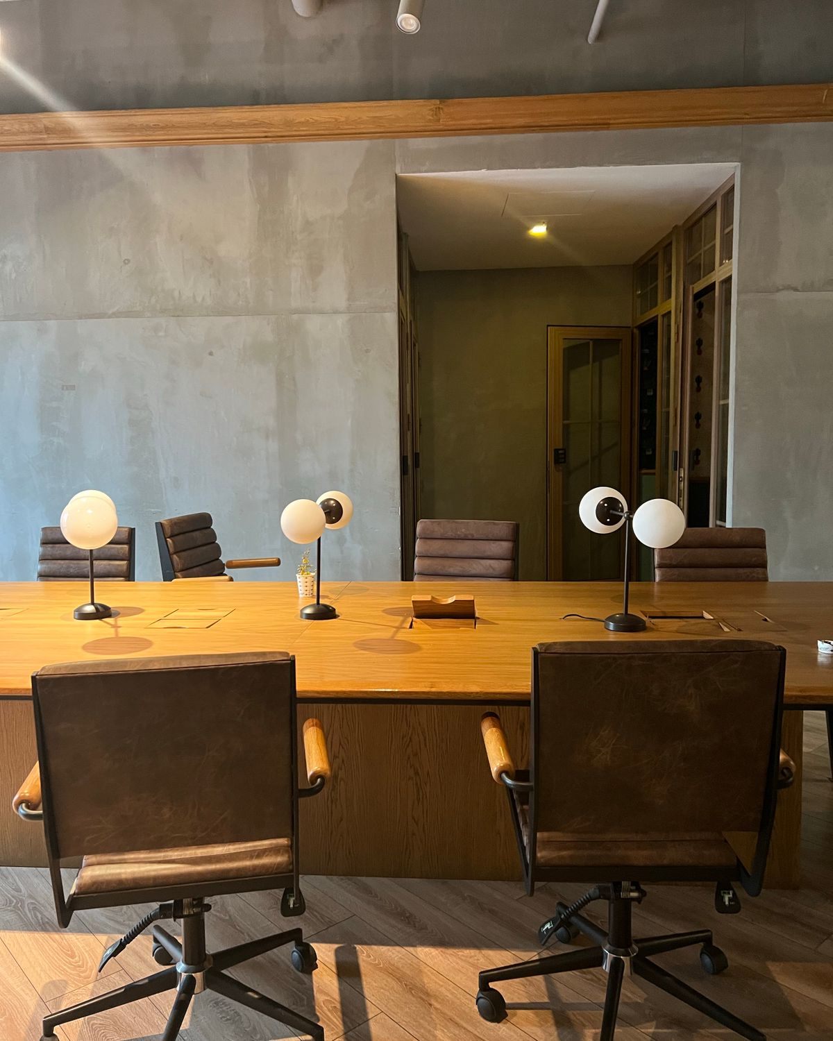 Meeting room with a long timber table and concrete walls